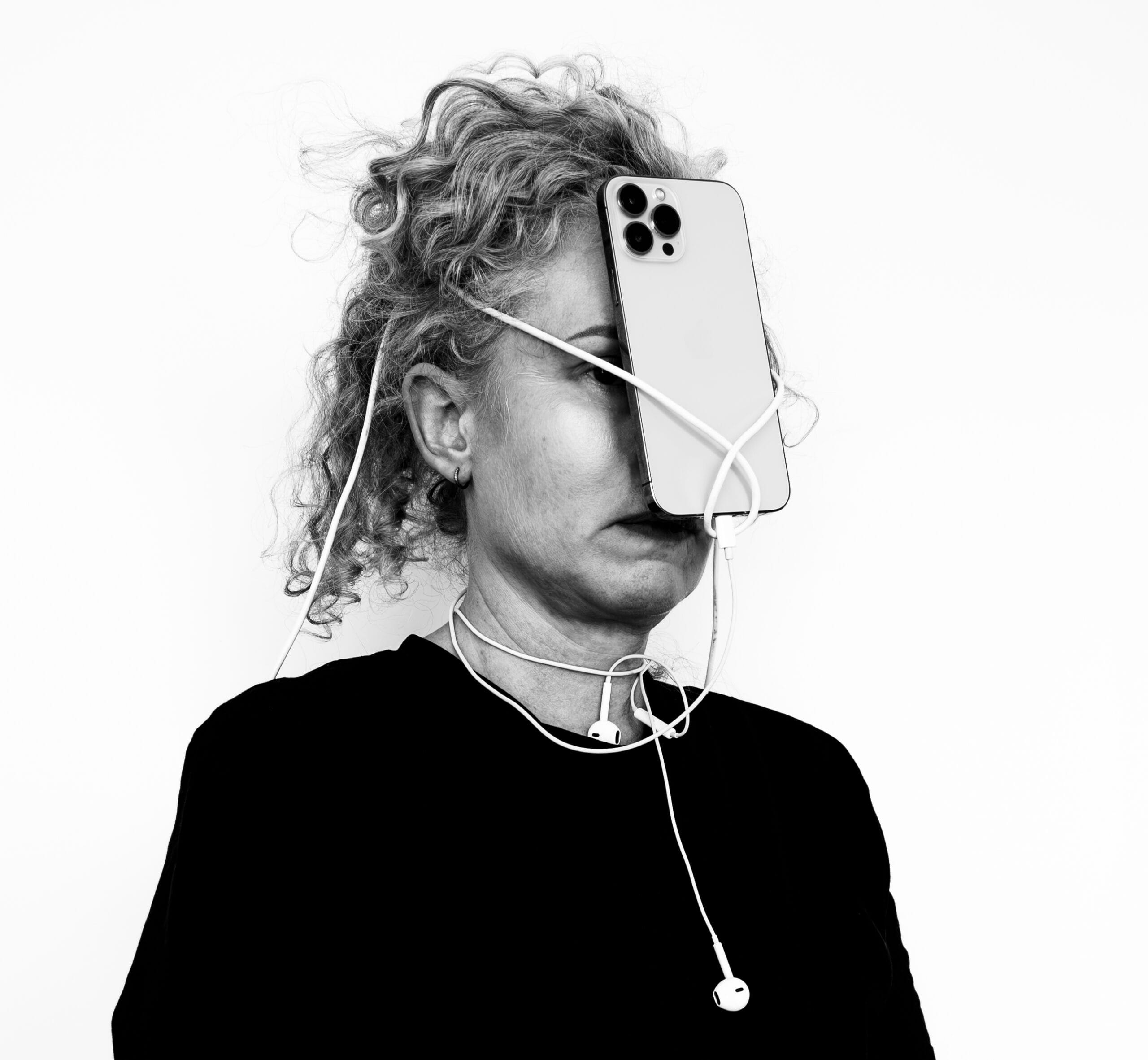 Svartvit bild på kvinna som har mobil fastsnurrad i ansiktet med snöre