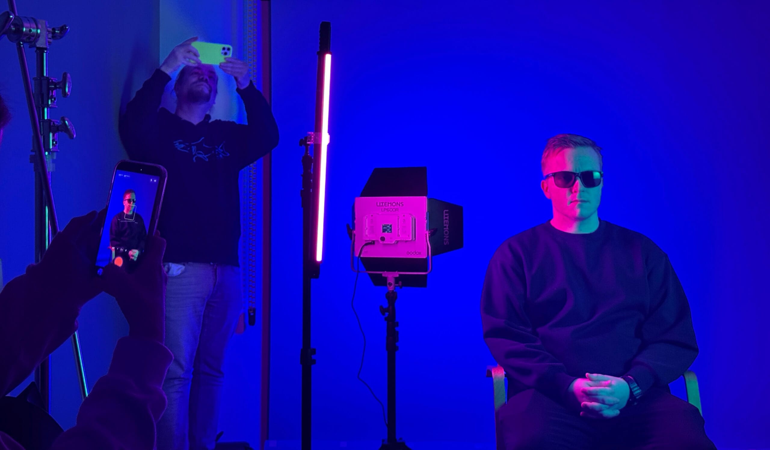 Mörkt rum med lysande blått och rött ljus, fotografering pågår av manlig modell